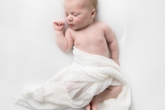 Sleeping newborn on a white blanket taken by Kimberly Kendall