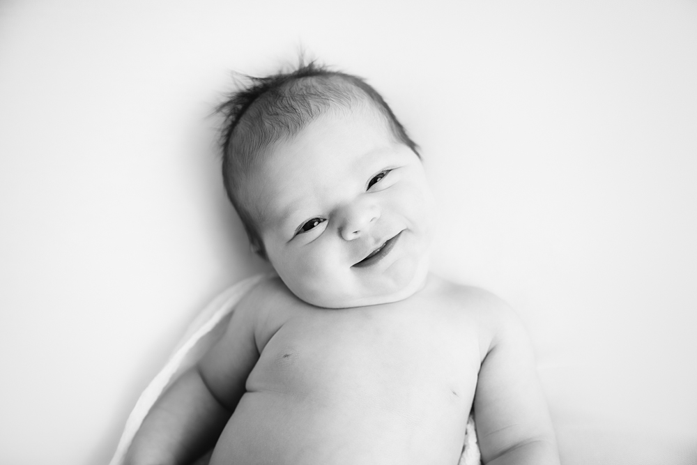 black and white image of a newborn smiling at the camera taken by Kimberly Kendall in Fairbanks